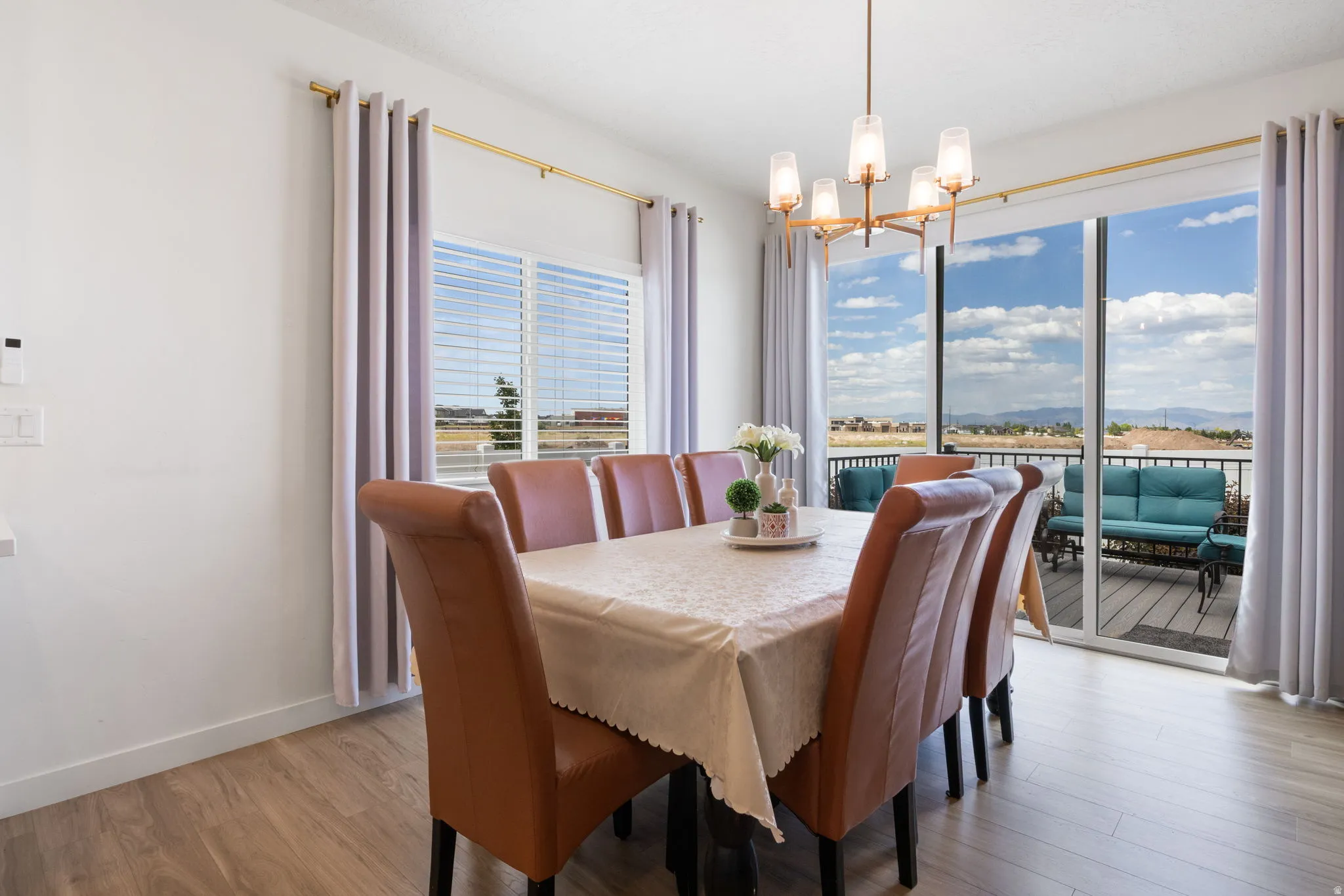 Dining area featuring wood-finish flooring, a contemporary chandelier, and a large sliding glass door opening to an outdoor deck