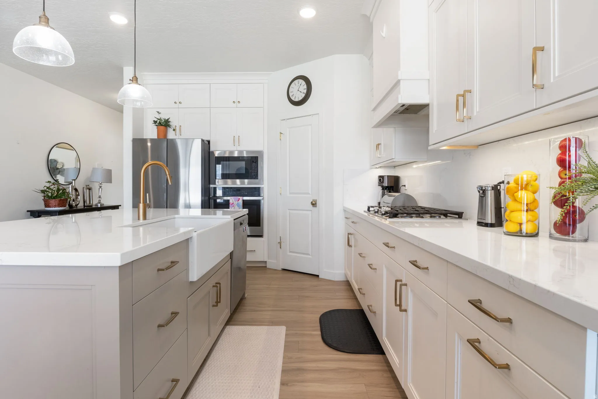 Modern kitchen featuring a large central island with a farmhouse sink, gold-toned faucet, and light gray cabinetry