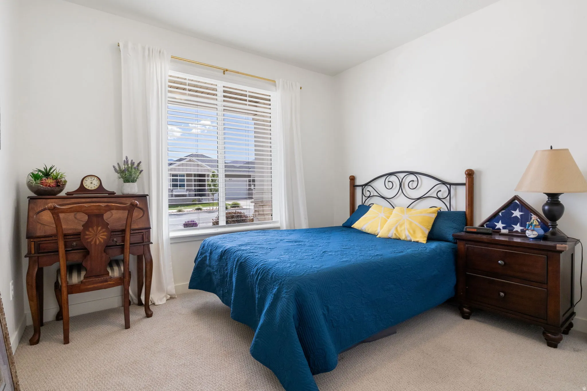 Carpeted room featuring a large window with blinds and white sheer curtains