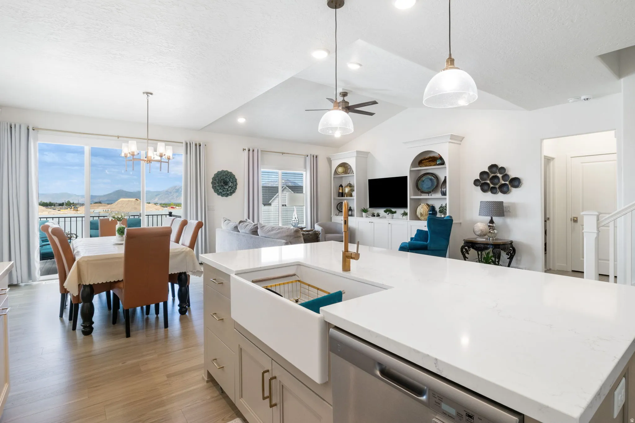 Modern kitchen island featuring a farmhouse-style sink with a gold-tone faucet, integrated dishwasher, and a light-toned countertop