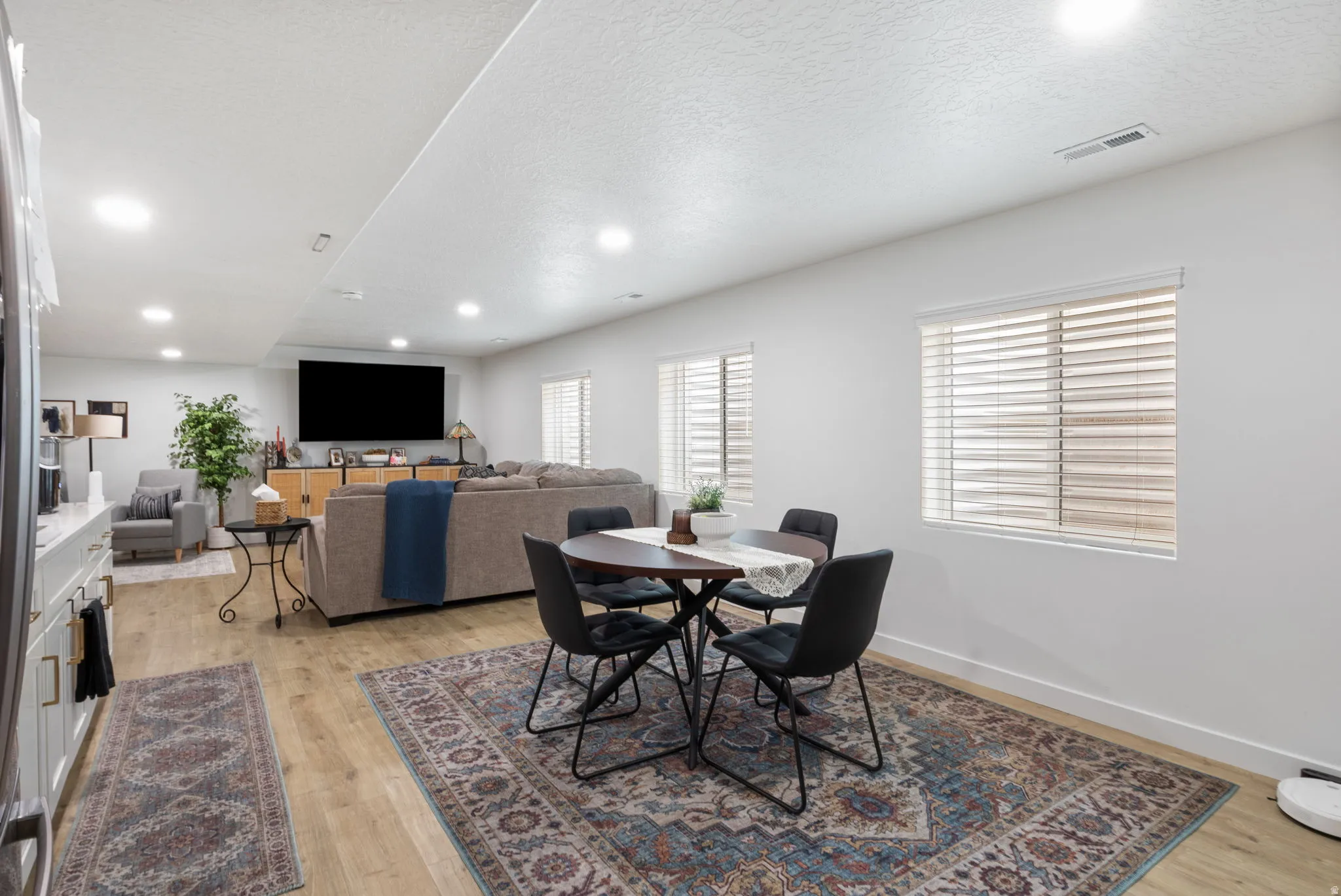 Spacious open-concept lower level featuring recessed lighting, wood-finish flooring, two window openings with blinds, and white baseboards