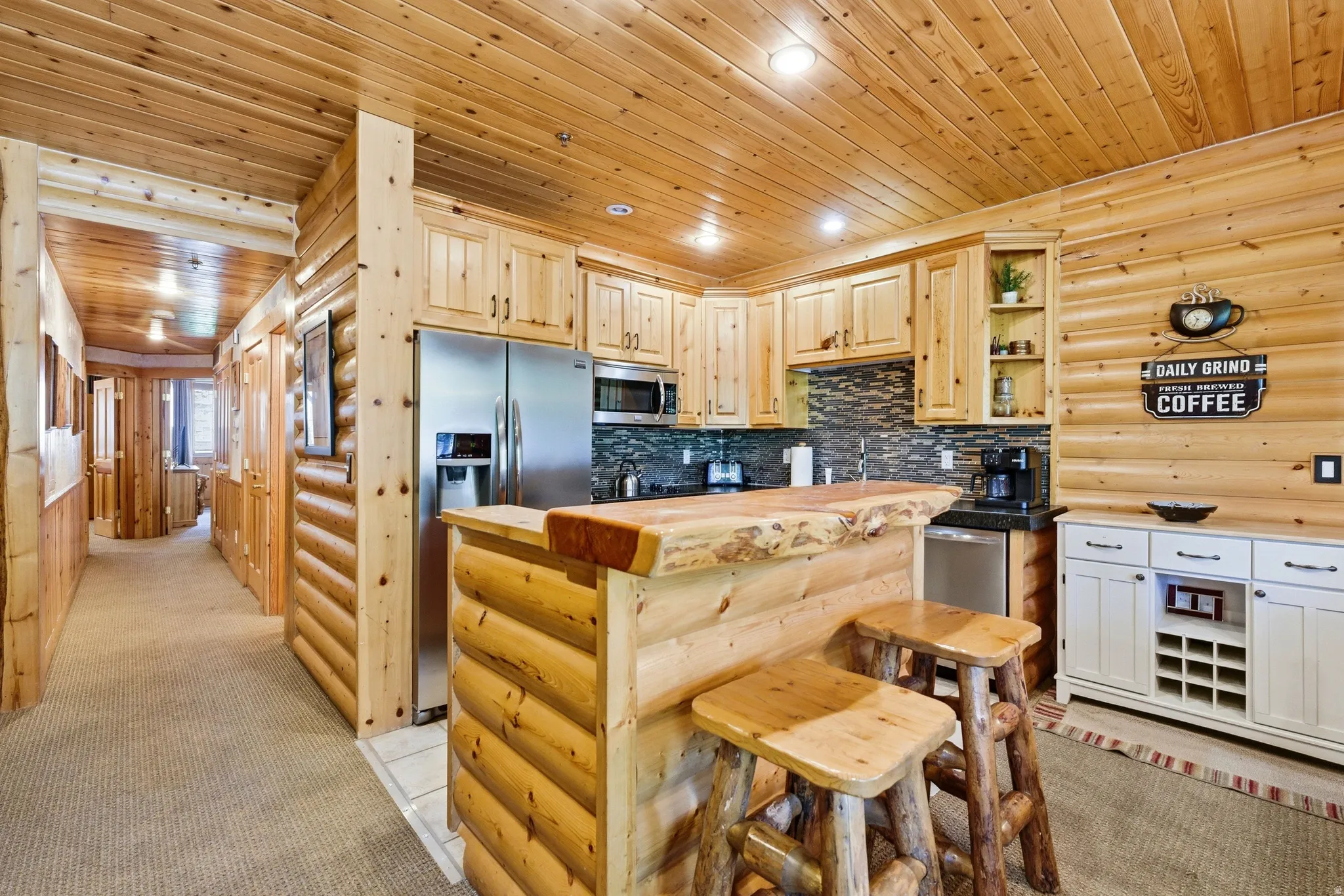 Kitchenette featuring a live-edge wood bar, stainless steel appliances, wood-paneled walls and ceiling, recessed lighting, and a textured tile backsplash
