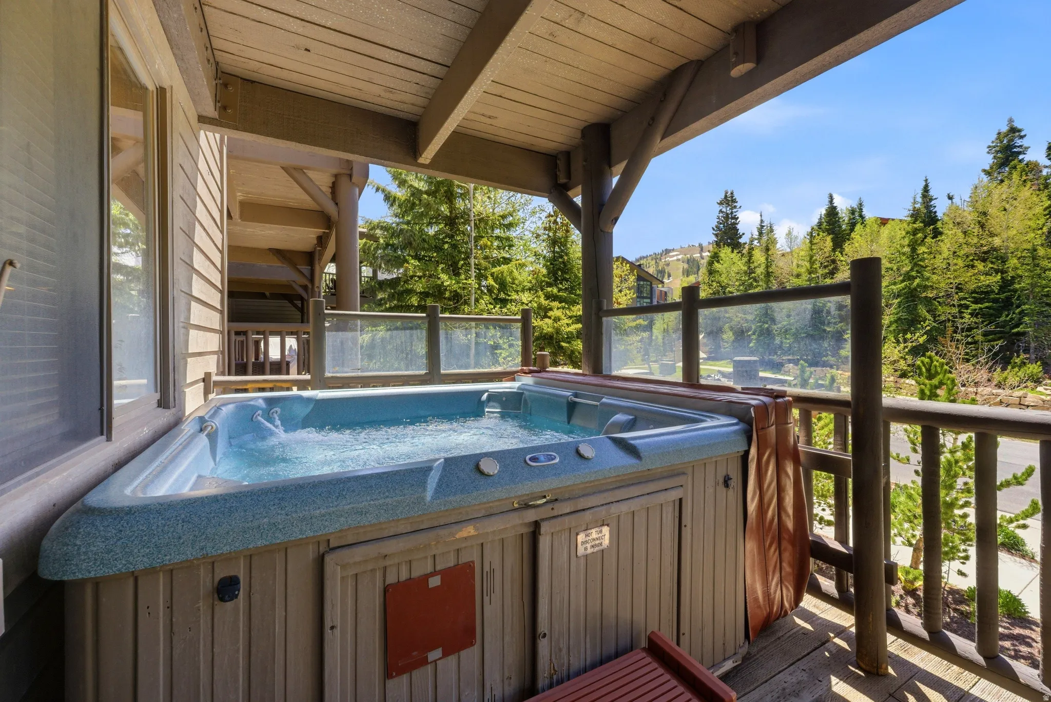 Outdoor hot tub on a private deck featuring wooden plank flooring and a wood-beamed ceiling