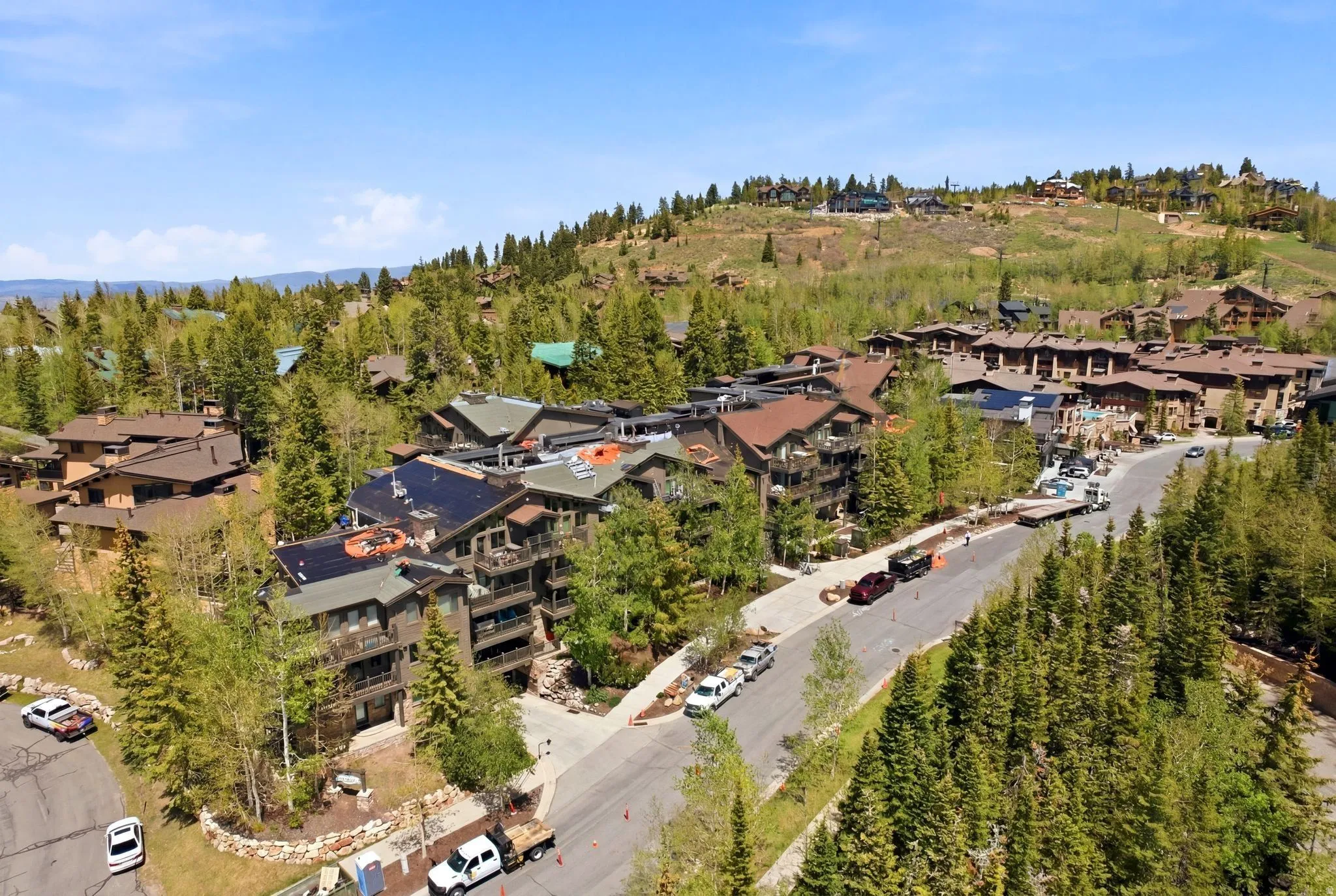 Contemporary multi-story buildings with balconies, surrounded by mature evergreen and deciduous trees