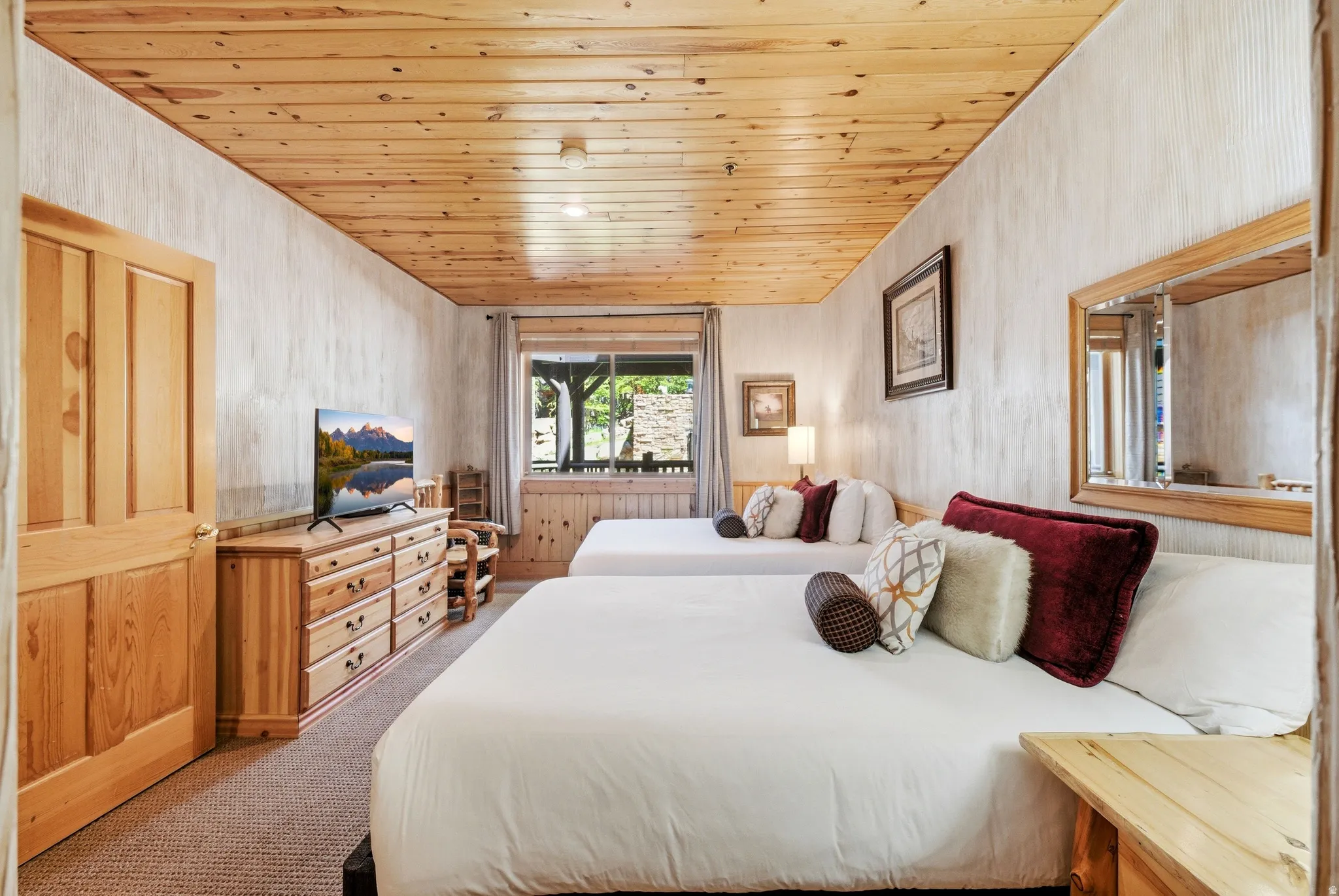 Bedroom featuring a natural wood plank ceiling, textured wall finish, and a large window with wood trim