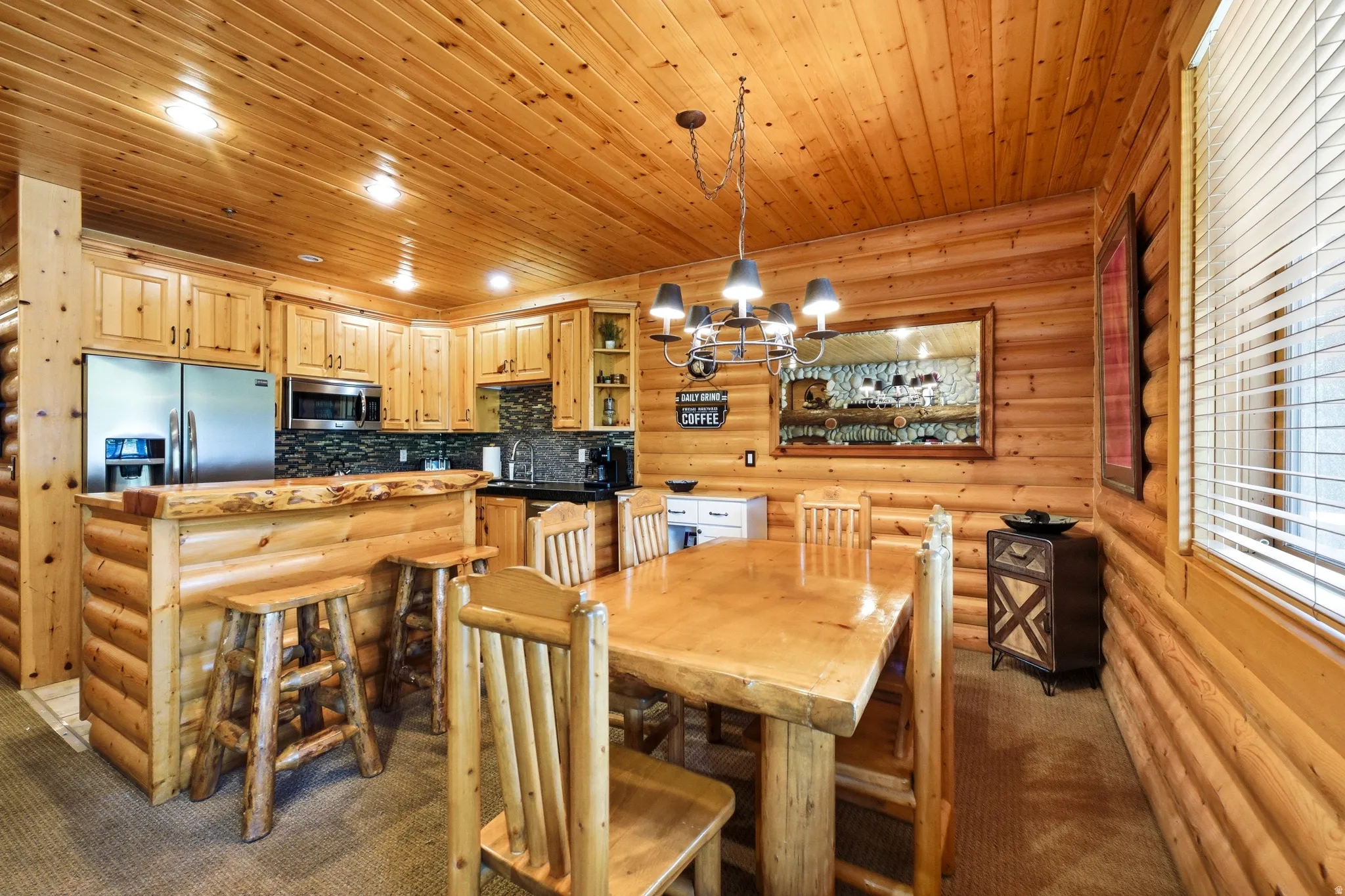 Open-concept dining and kitchen space featuring log-style walls and ceiling
