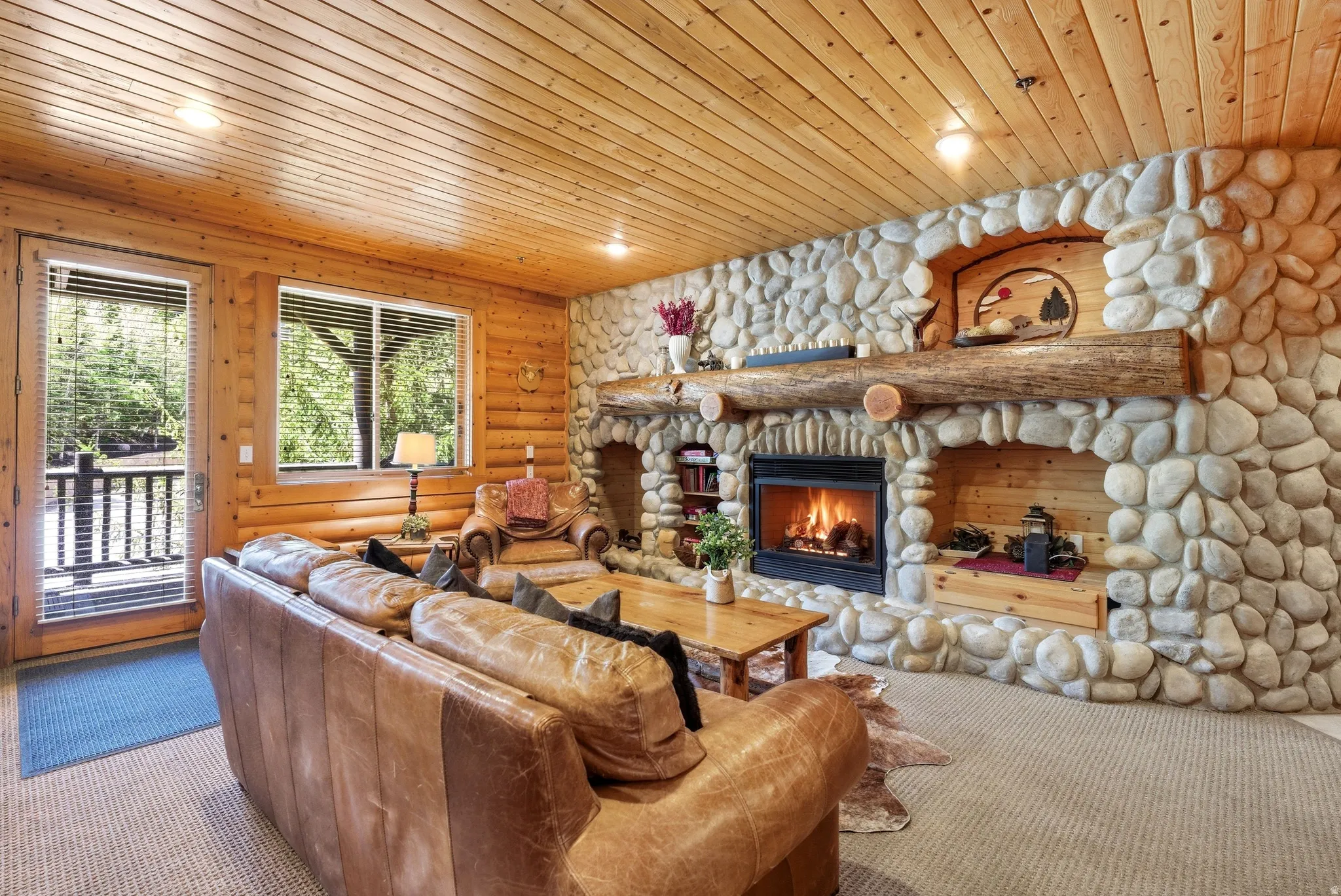 River rock fireplace with a substantial log mantel and built-in shelving