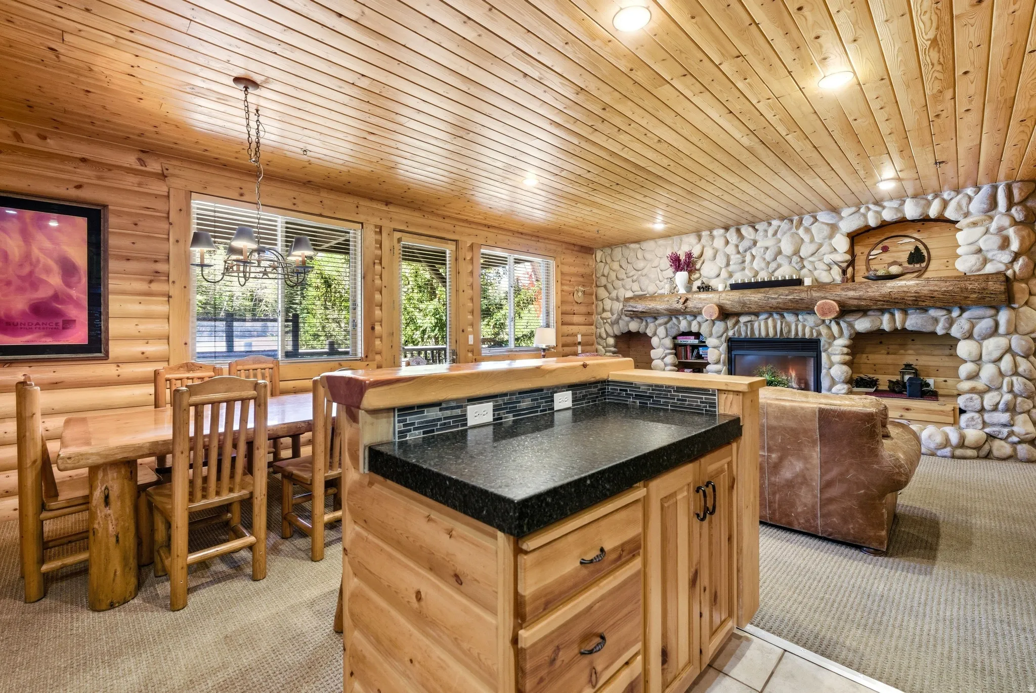 Open-concept living space with log walls and wood-paneled ceiling