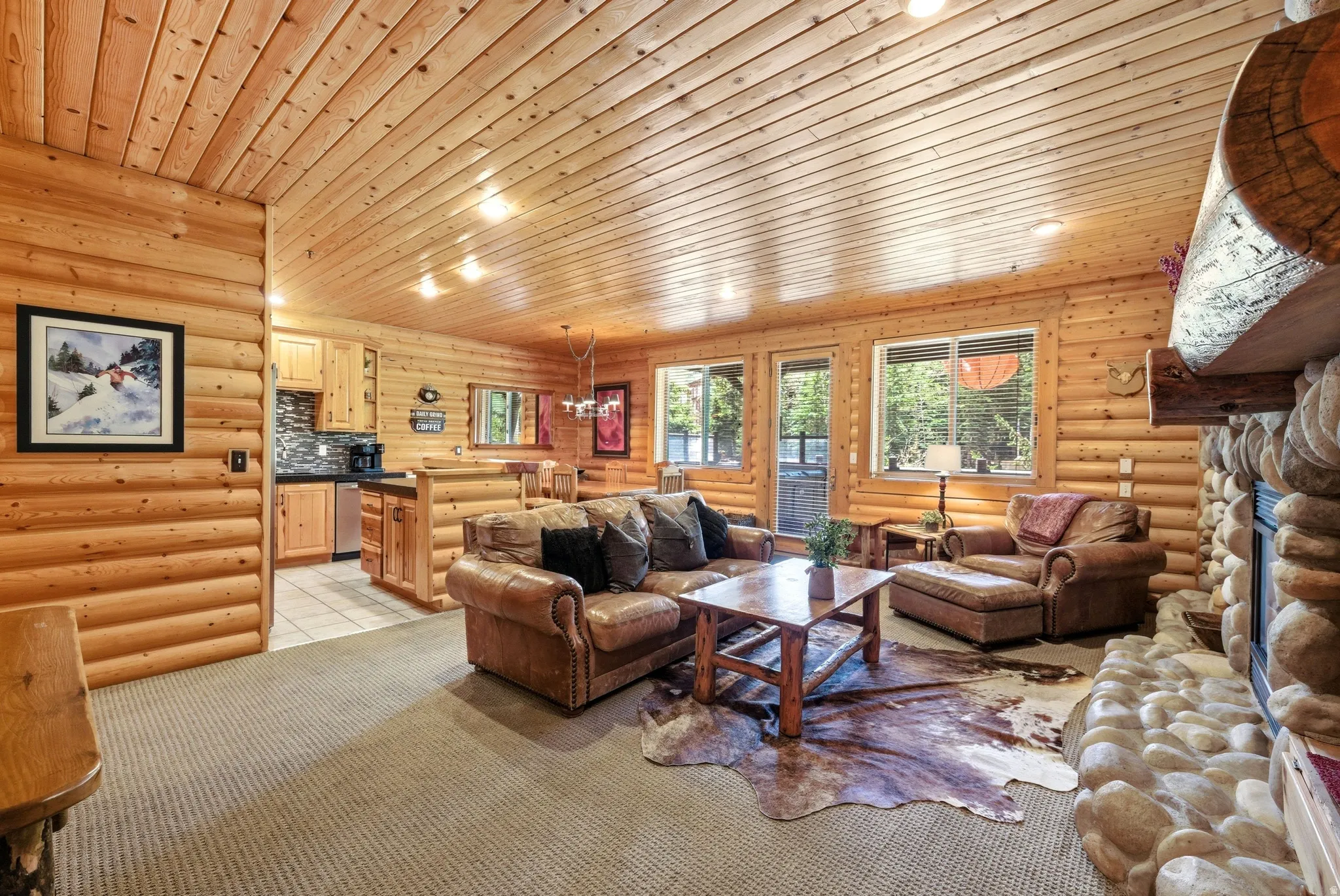 Open-concept living area featuring log-style walls and a wood-paneled ceiling