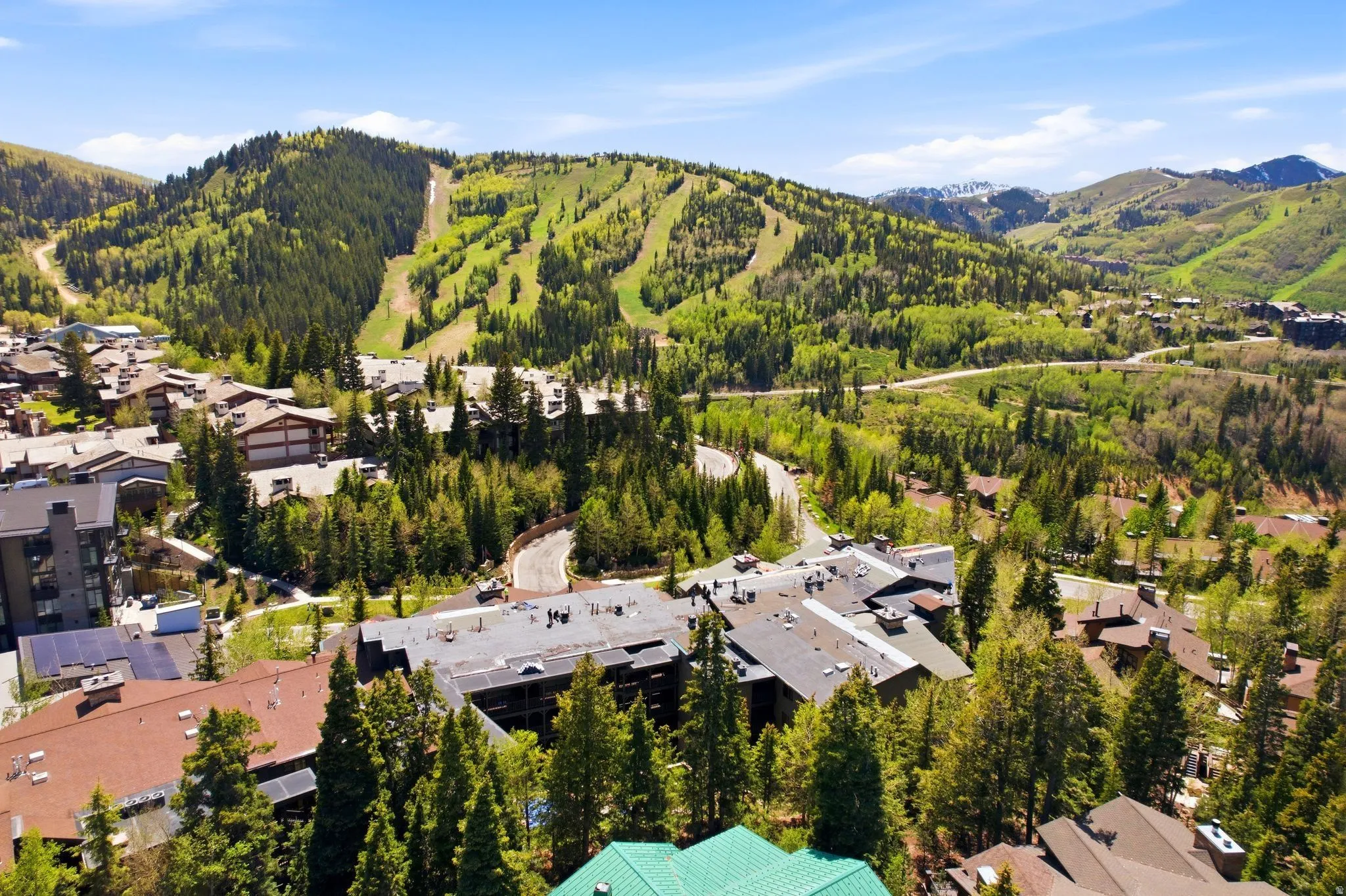 Expansive mountain landscape featuring ski slopes, mature evergreen trees, and a collection of buildings with various rooflines