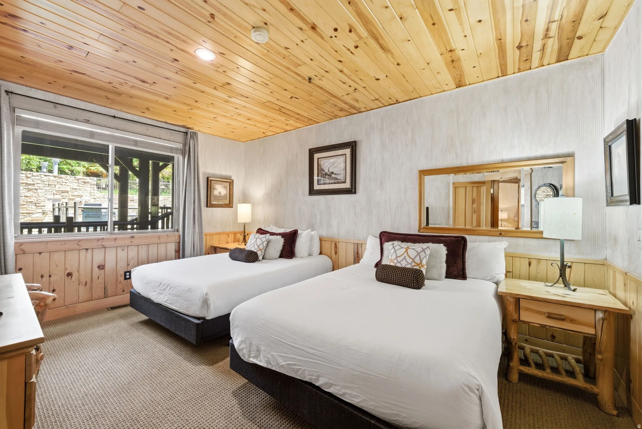 Bedroom featuring two beds with wood-paneled ceilings and wainscoting