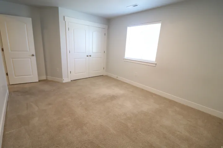 Neutral tone wall paint, light-colored carpet flooring, white trim, white window blind, and white paneled doors