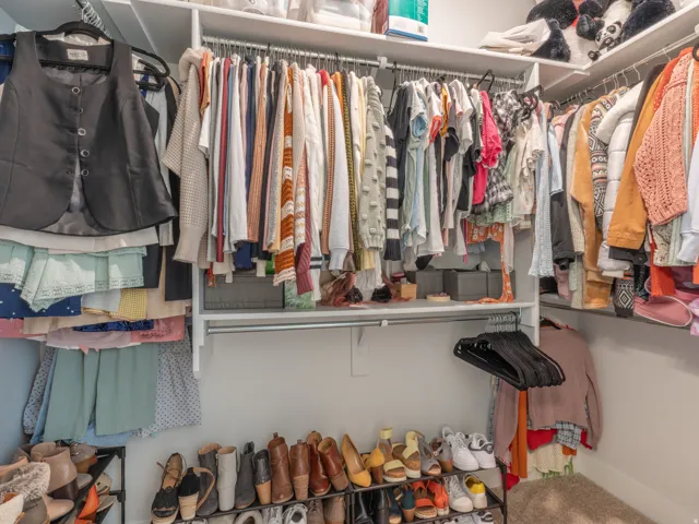 Walk-in closet featuring white shelving, multiple hanging rods, and ample storage space