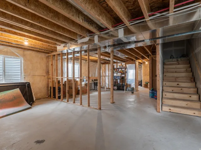 Unfinished basement offering substantial floor space and visible framing