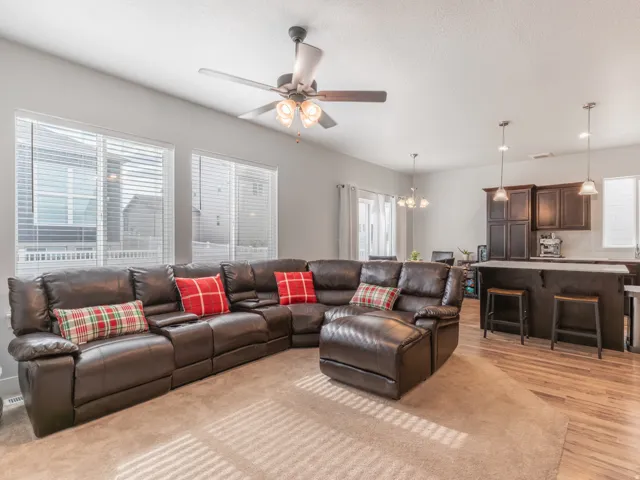 Open-concept living space featuring a ceiling fan, multiple windows with blinds, recessed lighting, and wood-finish flooring