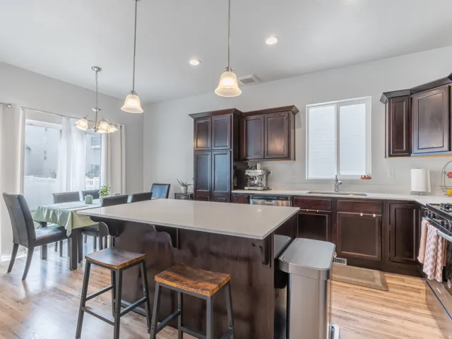 Kitchen featuring wood-finish flooring, dark wood cabinetry, and white countertops