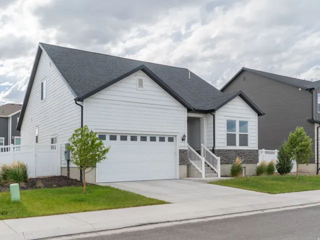 Modern ranch-style residence featuring white siding, a dark shingle roof, and stone facade accents