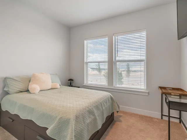 Neutral-toned wall paint and carpeting complement two large windows, featuring white blinds and trim