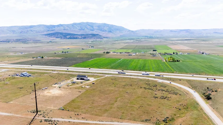 Expansive agricultural land featuring a highway, distant mountains, and established fields