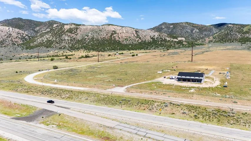 Modern-style residence featuring a dark exterior with a black roof, set on a large lot with mountainous terrain in the background