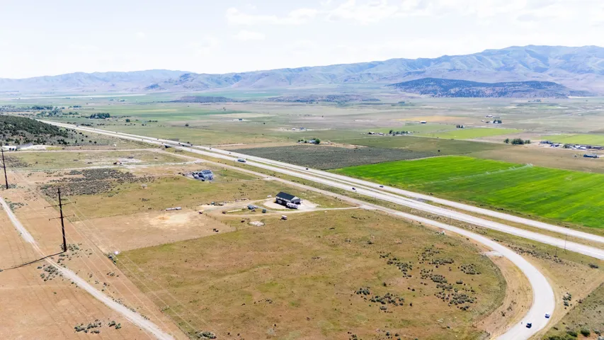 Expansive rural property featuring highway frontage, agricultural fields, and mountainous terrain