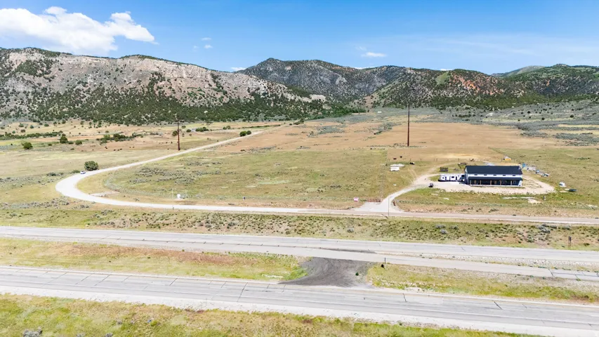 Expansive land featuring a single-story building with a dark roof and mountain scenery