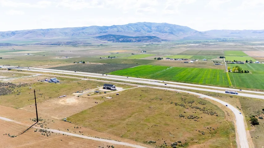 Expansive rural landscape featuring a highway, agricultural fields, and distant mountains