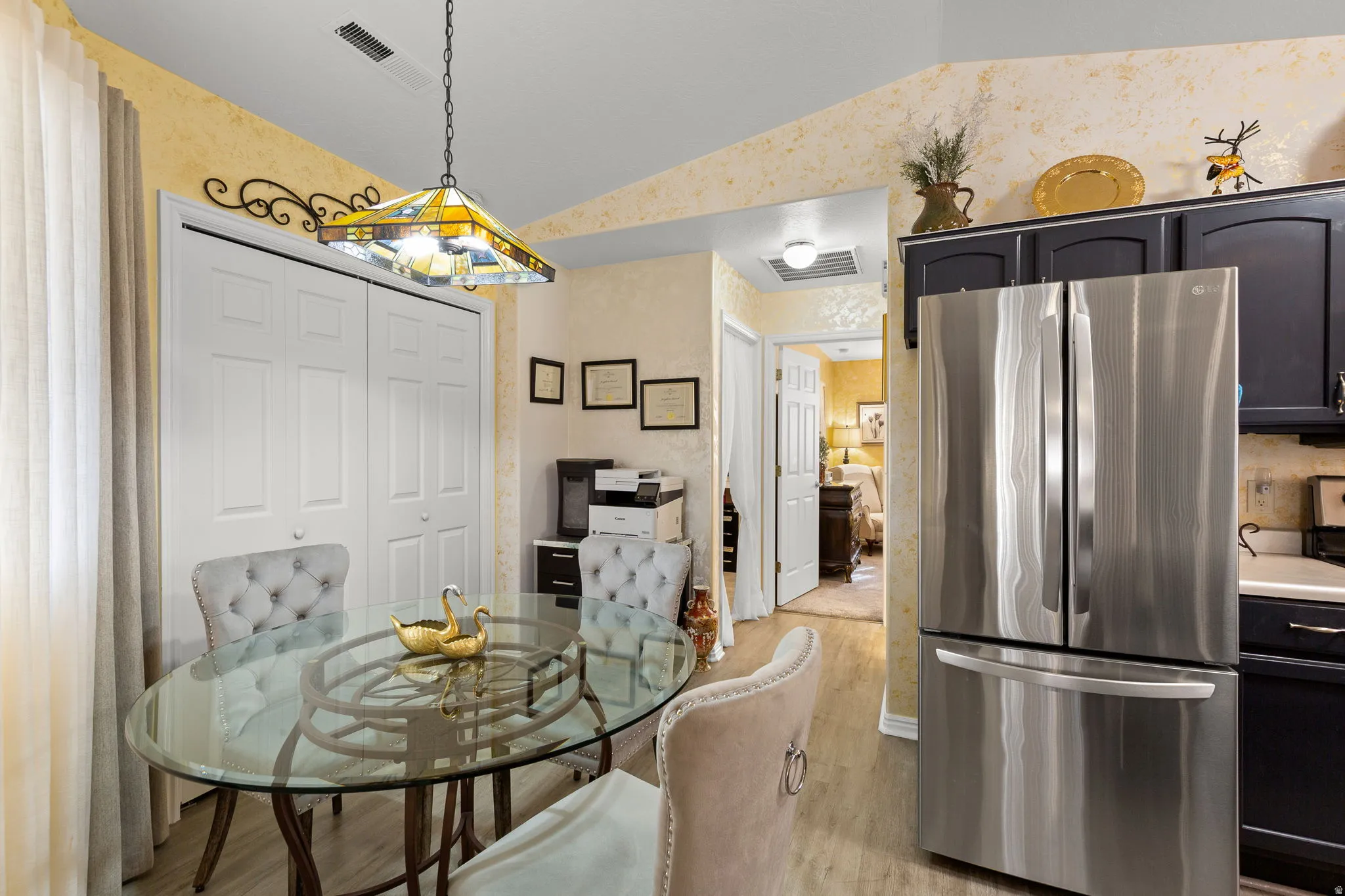 Kitchen area featuring a stainless steel French door refrigerator, dark cabinetry, and light countertops