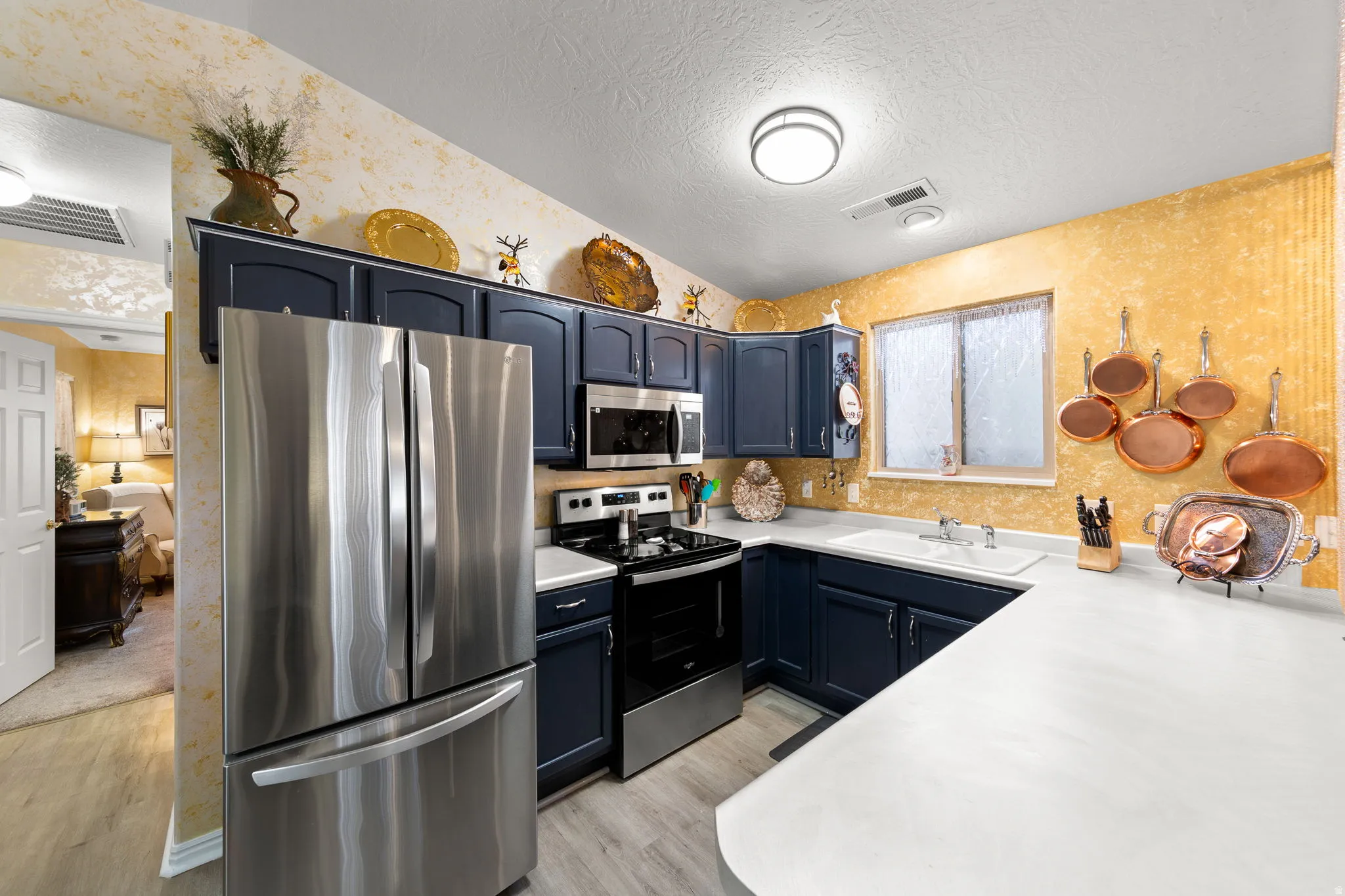 Kitchen featuring dark cabinetry with light countertops, stainless steel appliances, and wood-finish flooring
