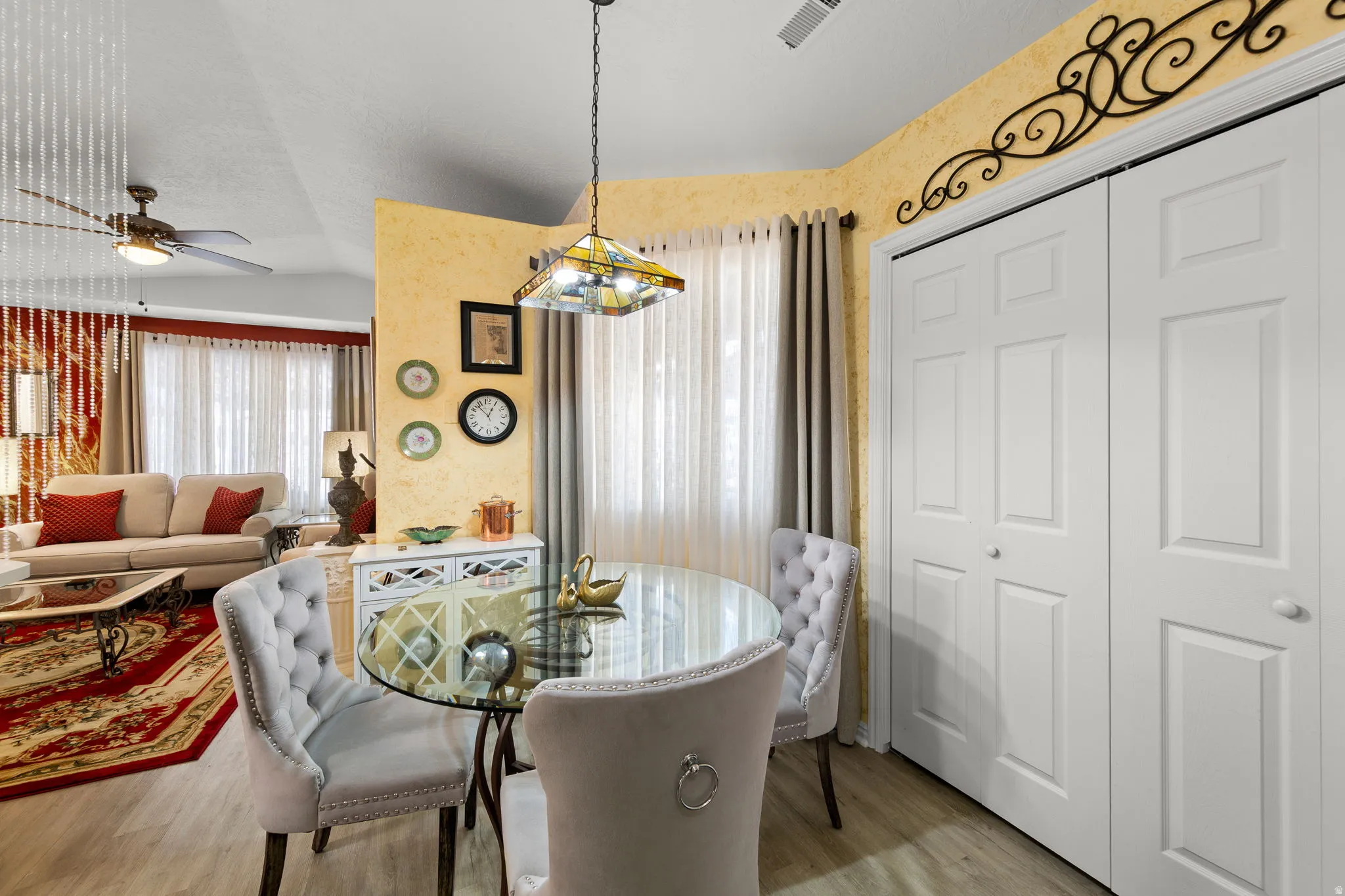 Dining area featuring wood-finish flooring, a glass-top table with a decorative base, and a stained glass light fixture