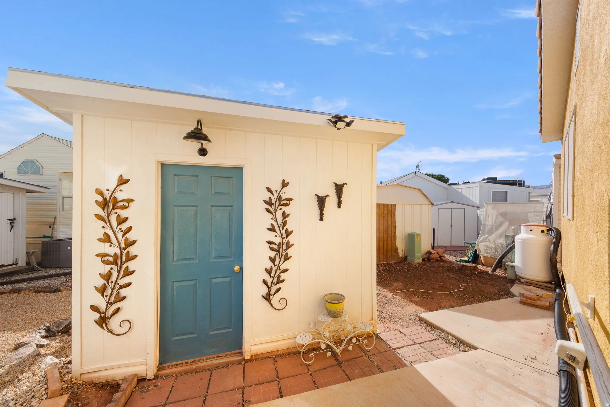 Detached accessory structure featuring a blue paneled door, exterior wall sconce, and decorative wall accents