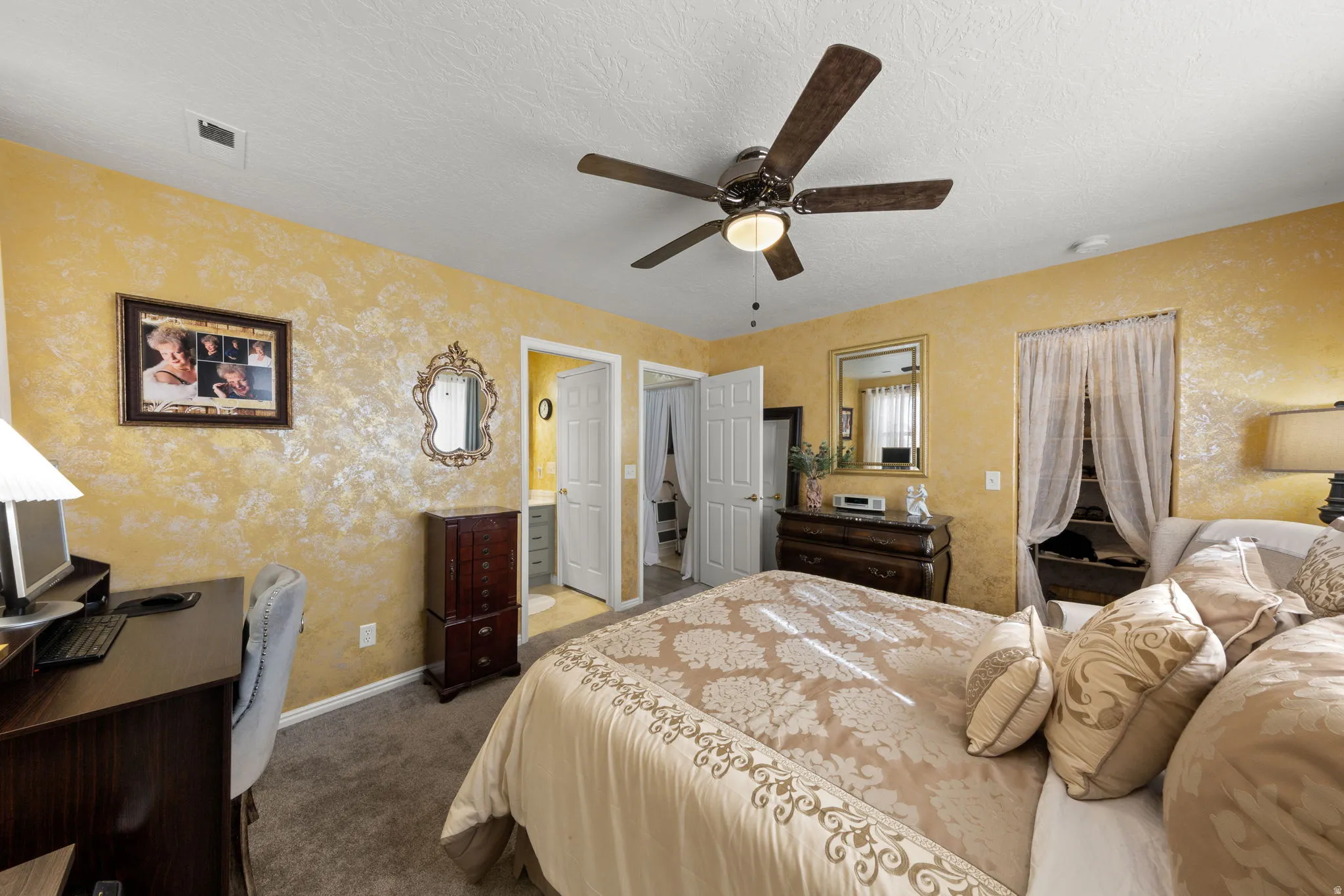 Bedroom featuring textured walls, carpet flooring, a ceiling fan with light fixture, and two panel doors