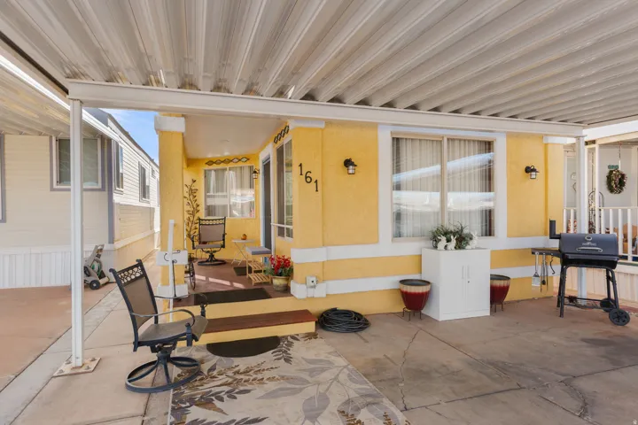 Covered patio area featuring a concrete slab, a small raised porch with steps, and exterior wall sconces