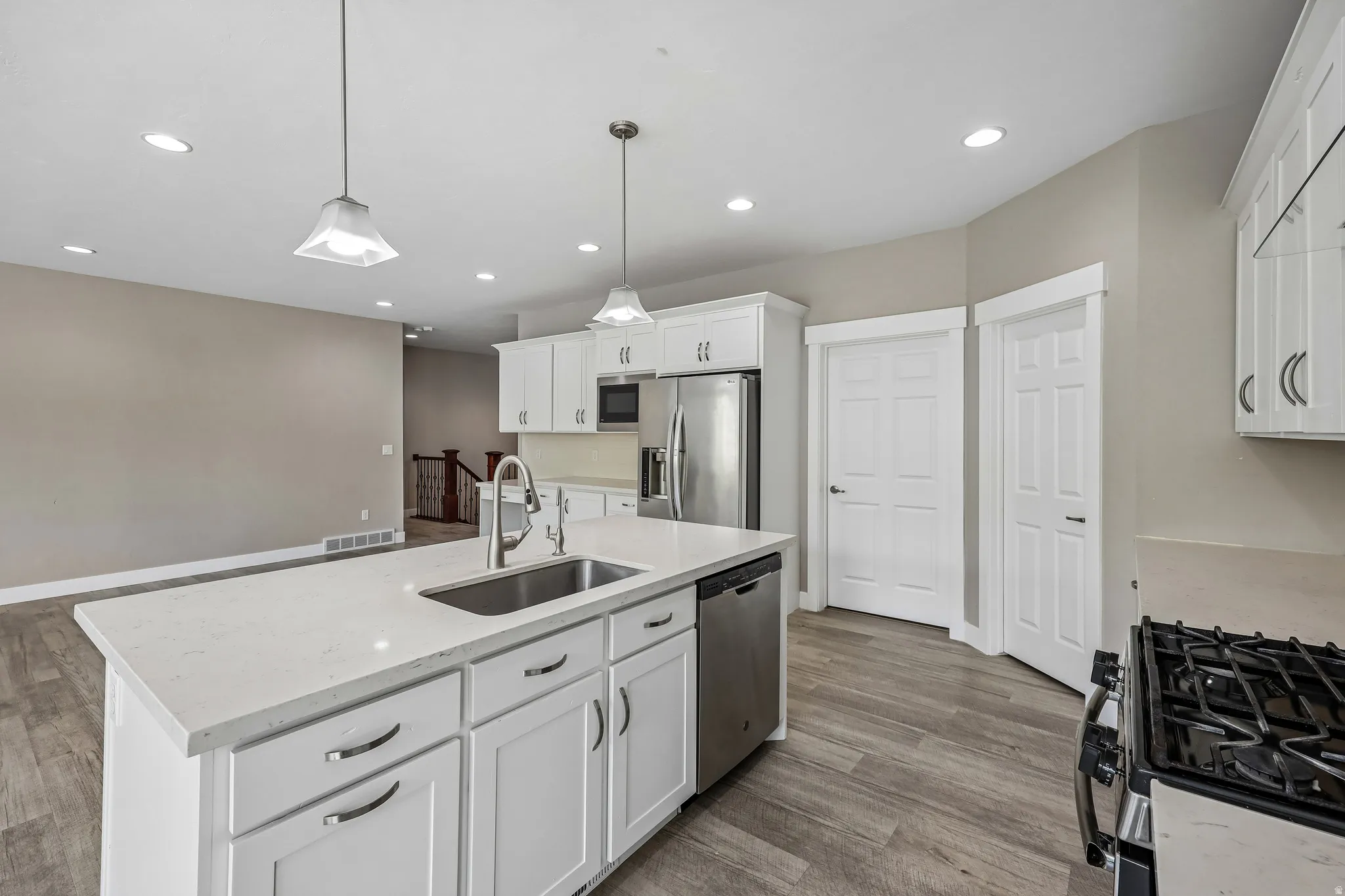 Kitchen with a large island featuring a stainless steel sink and white quartz countertop