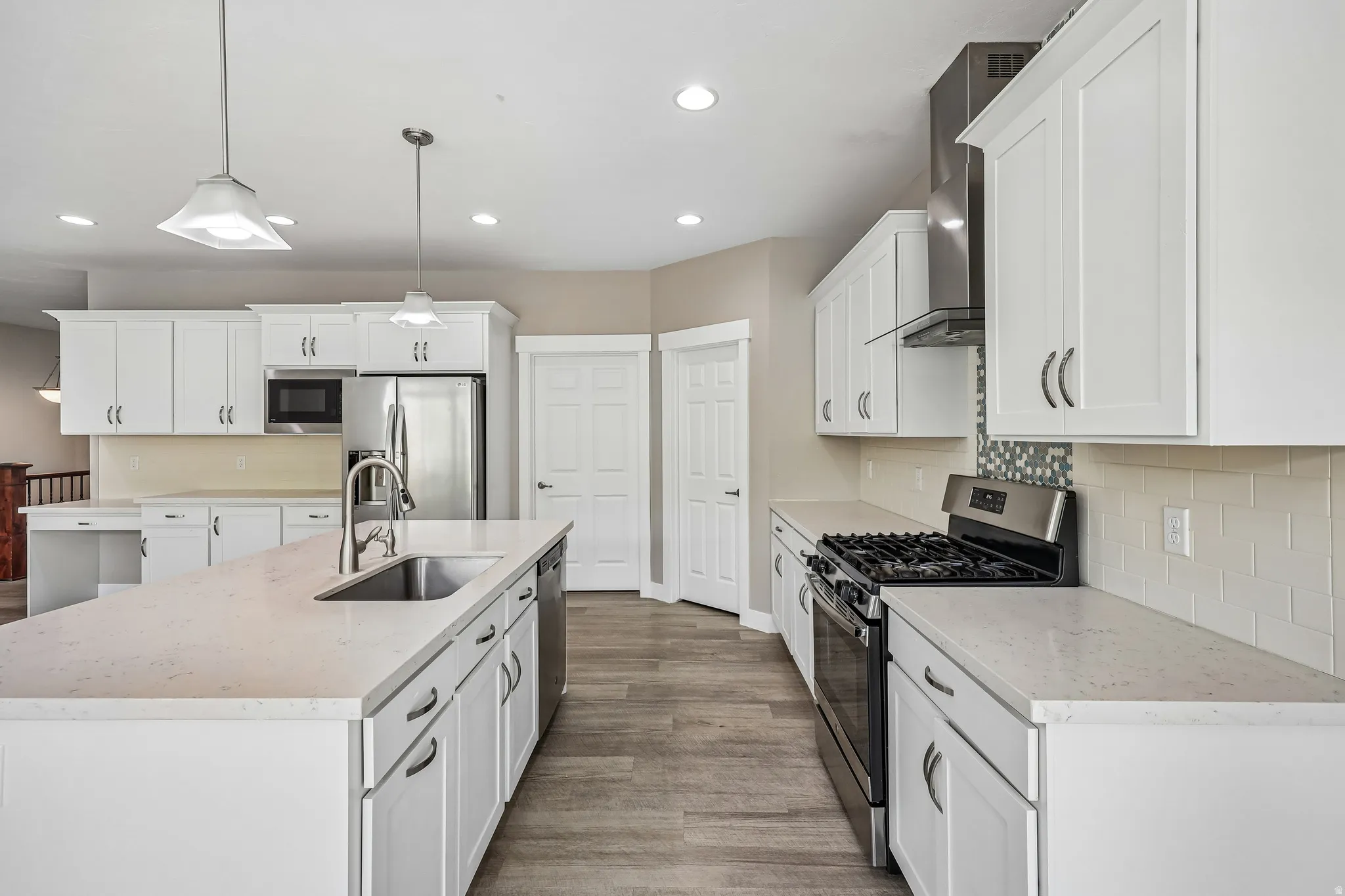 Modern kitchen featuring white cabinetry, light-toned countertops, and wood-finish flooring