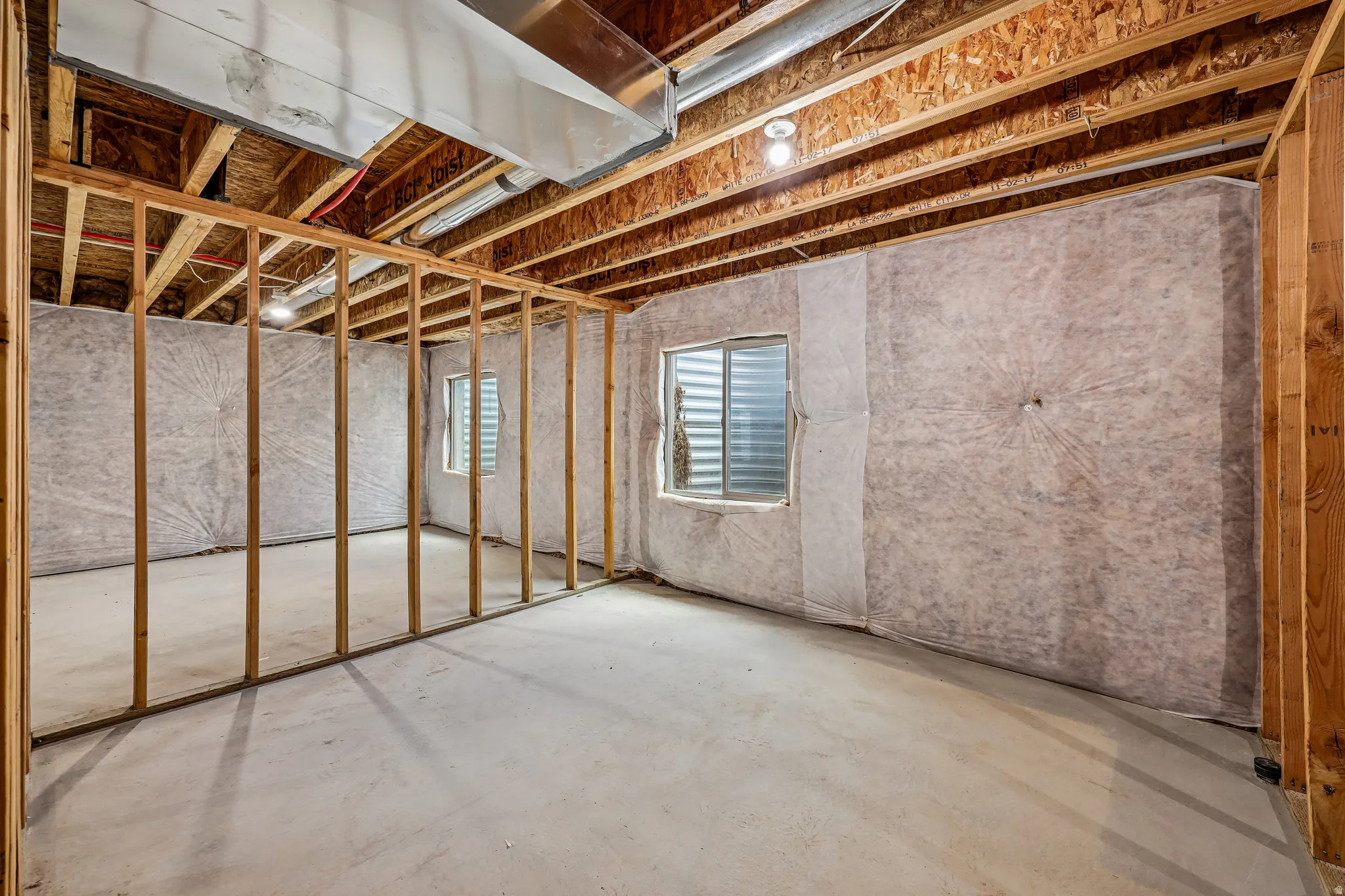 Unfinished basement space featuring exposed wooden joists, concrete flooring, and partial wall framing