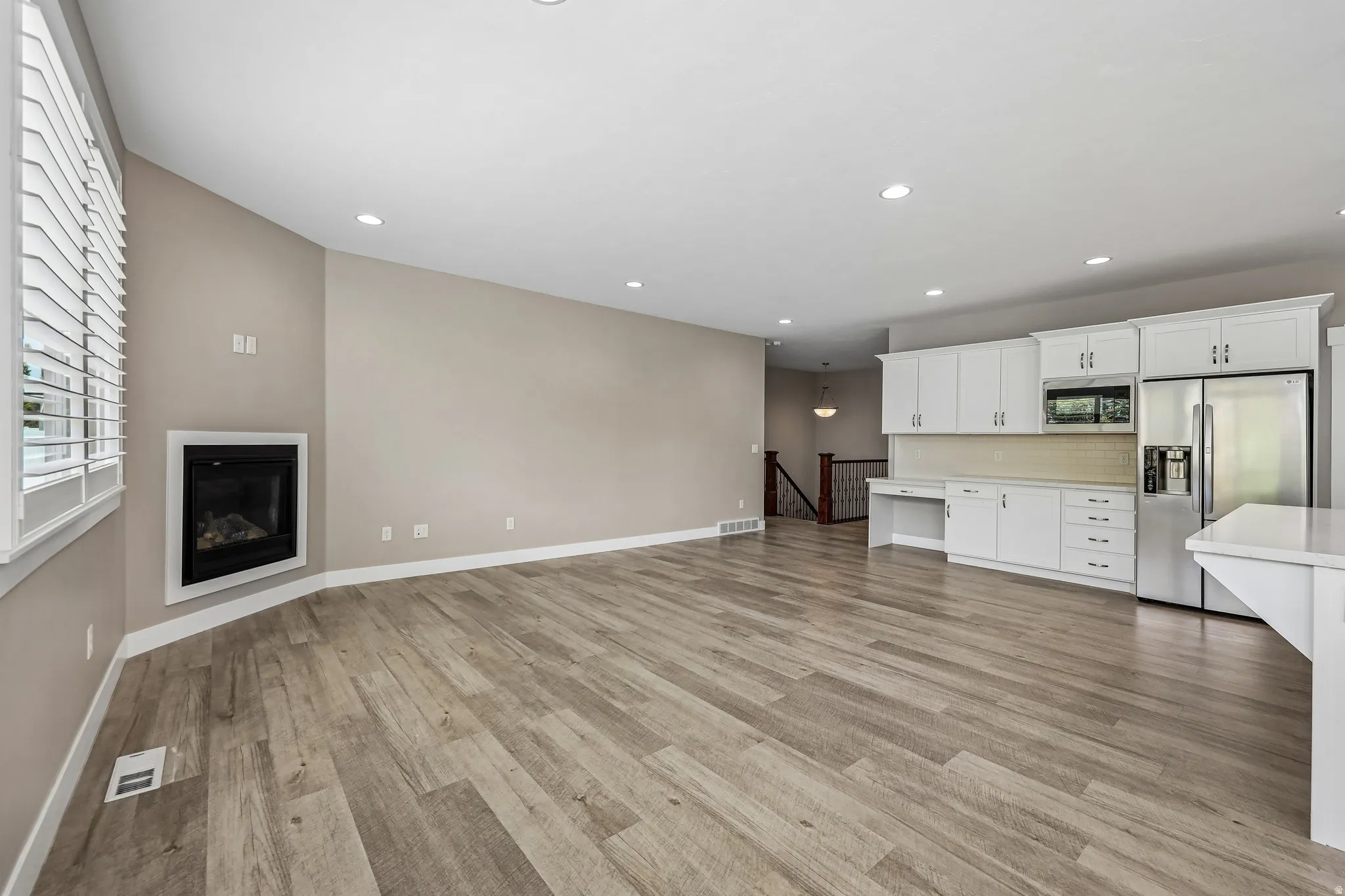 Open-concept living space featuring wood-finish flooring, recessed lighting, and a corner fireplace