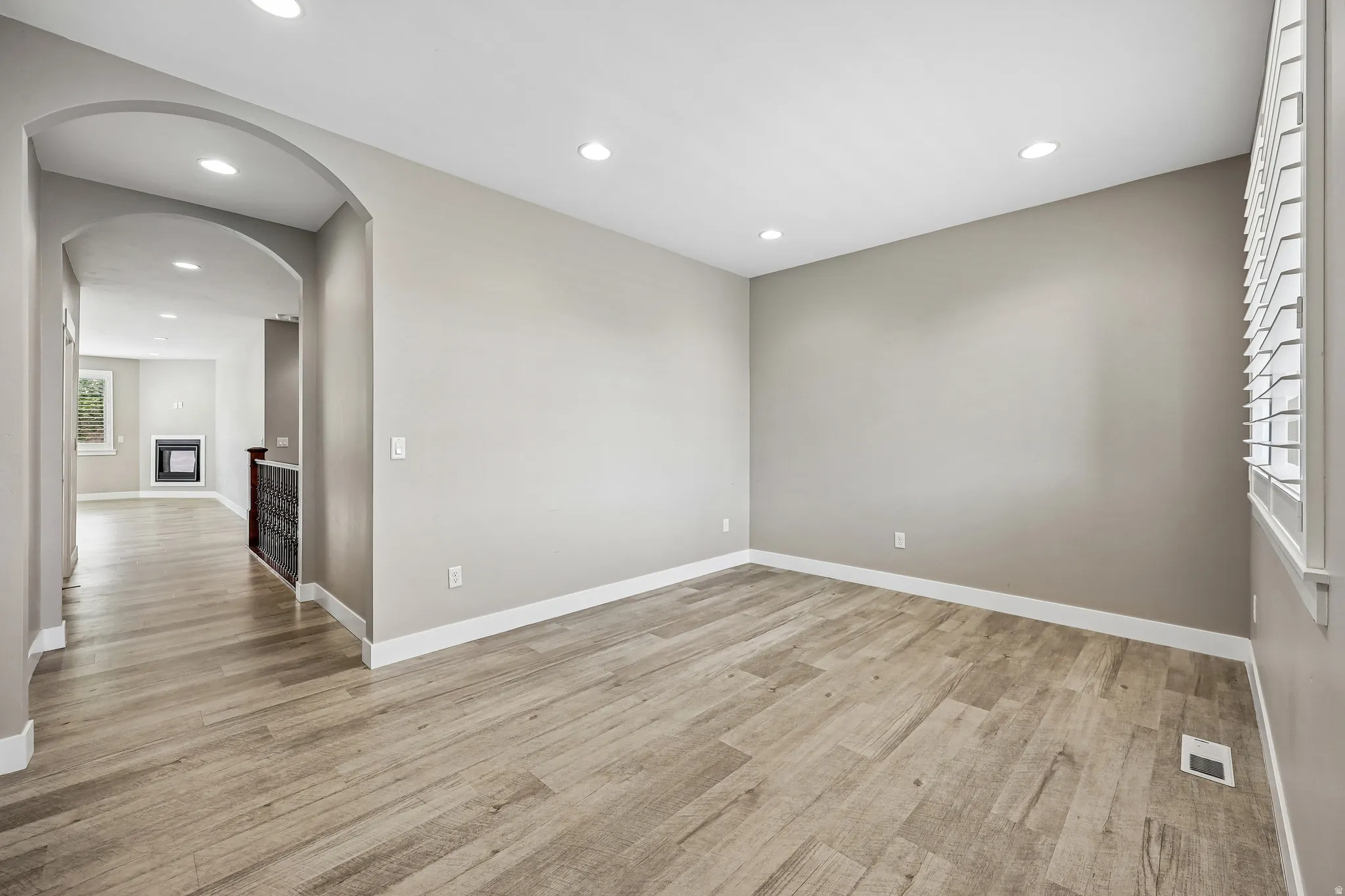 Light wood-finish flooring extending into an arched doorway
