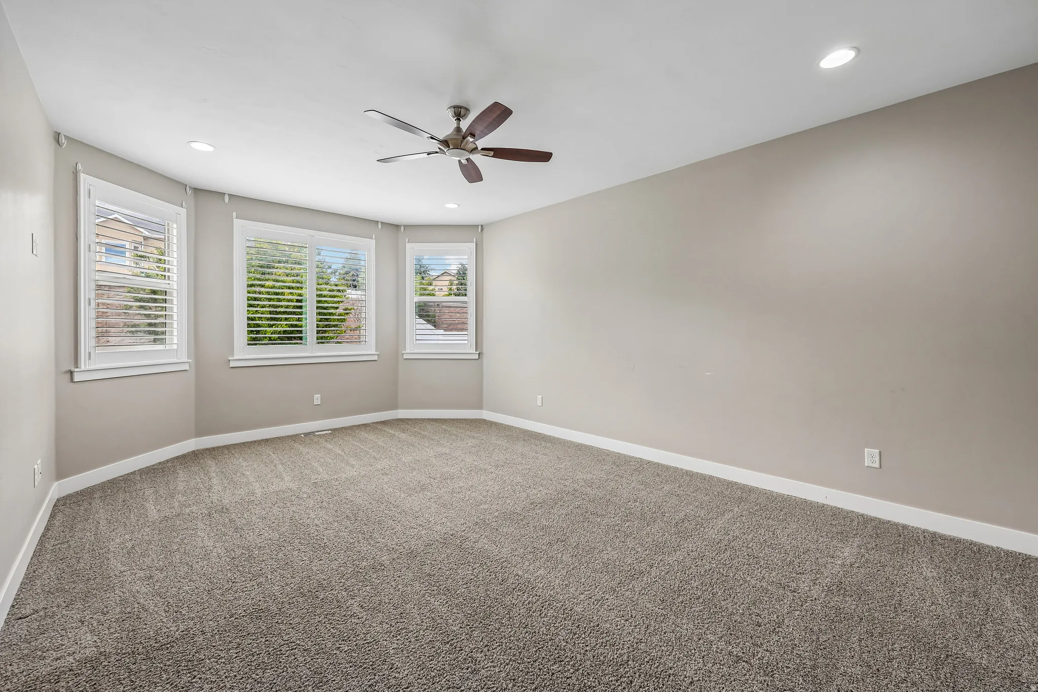 Spacious room featuring neutral carpet flooring, recessed lighting, and a ceiling fan