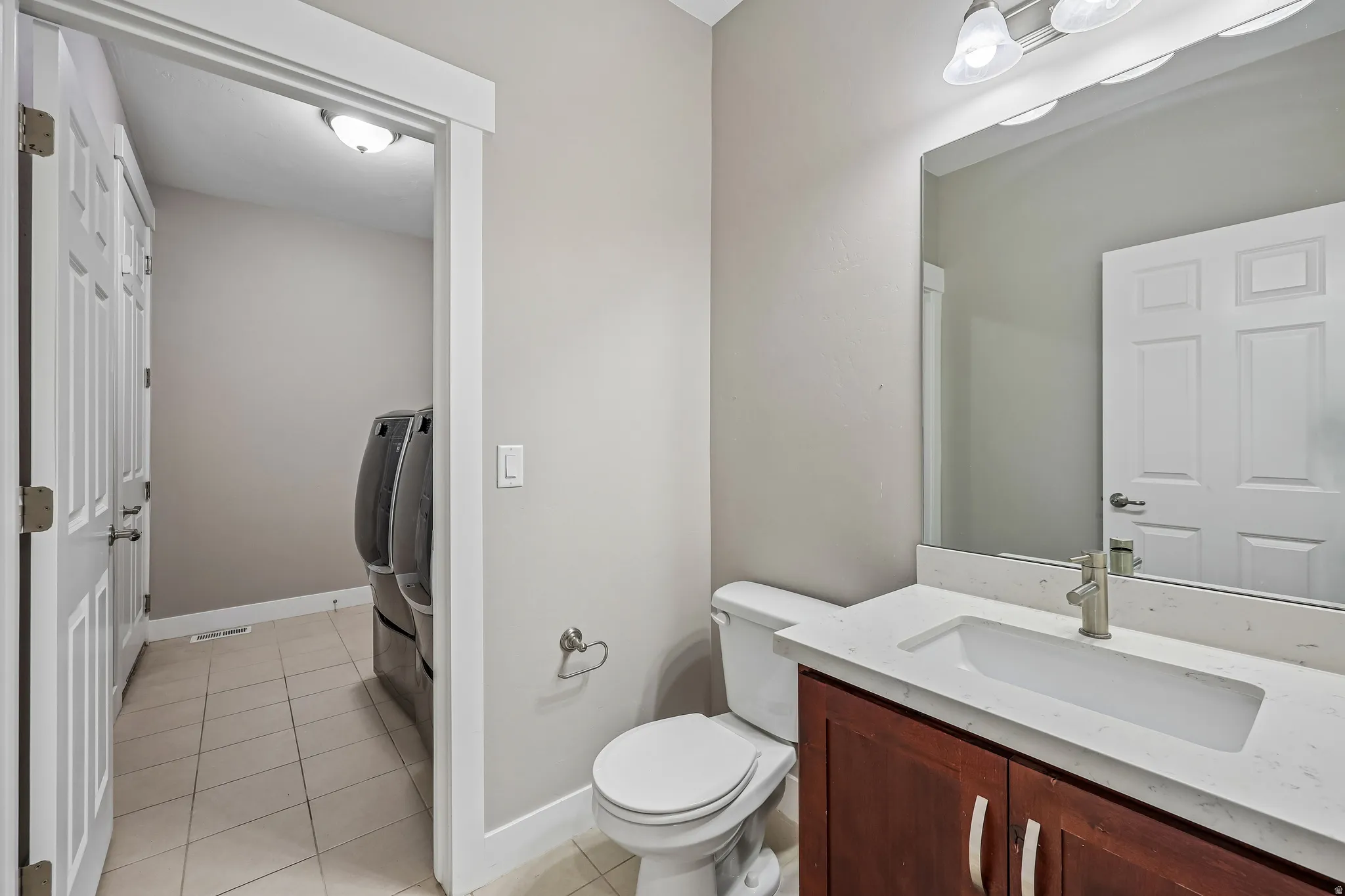 Bathroom featuring a wood-finish vanity with a light-toned countertop, an undermount sink, and a brushed nickel faucet