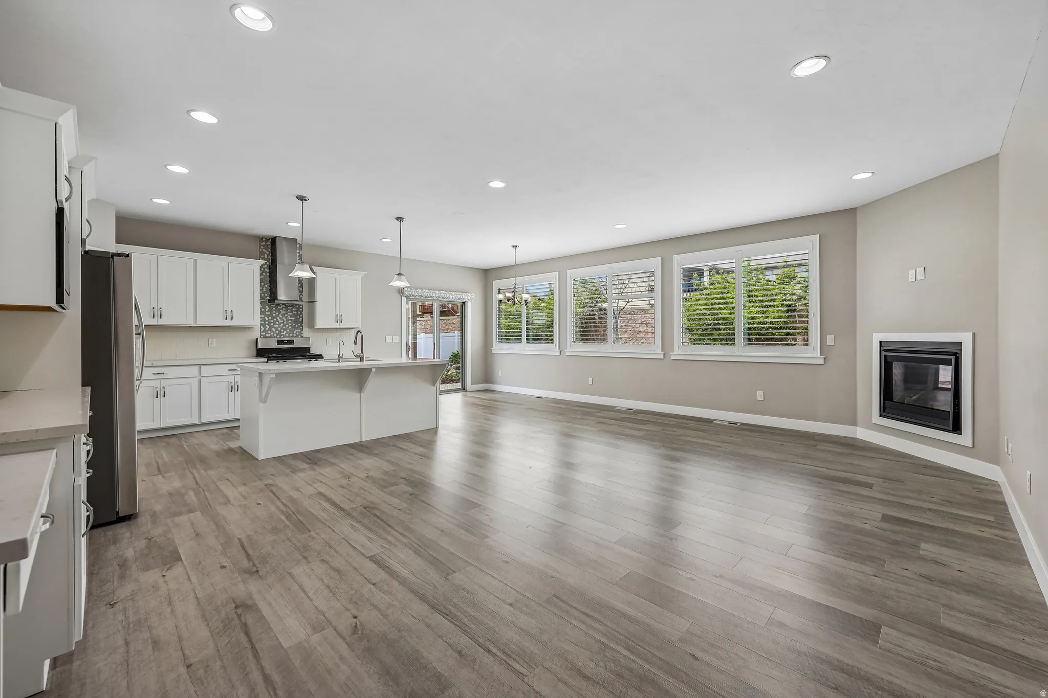 Open-concept living space featuring wood-finish flooring, recessed lighting, and an integrated kitchen