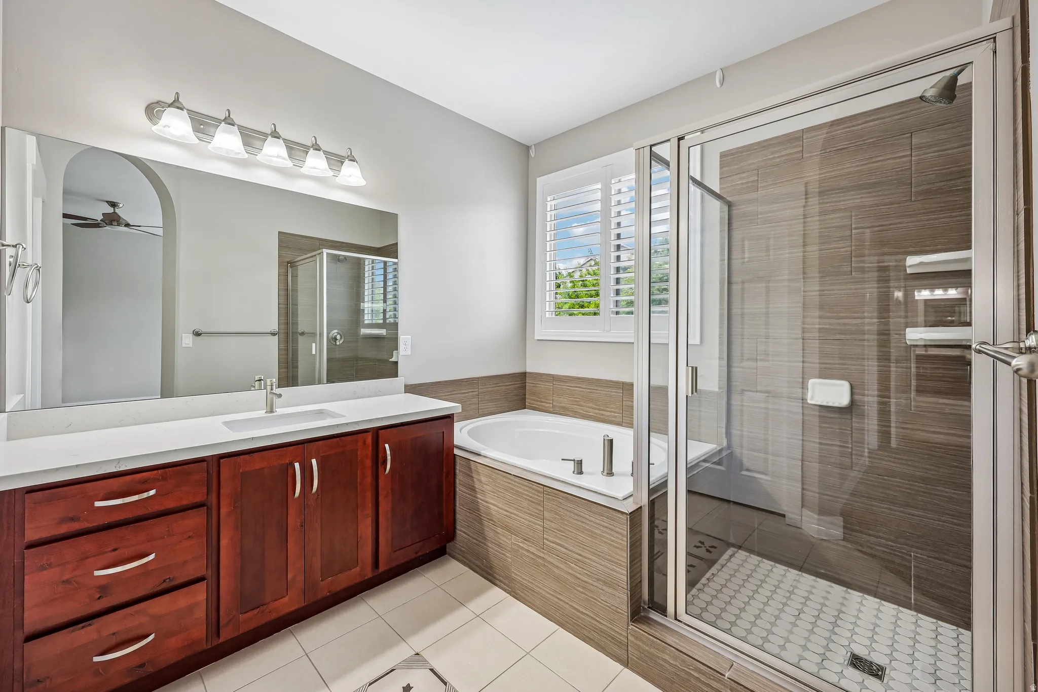 Bathroom featuring a spacious vanity with a white countertop and wood-finish cabinetry, a large mirror, and an overhead light fixture