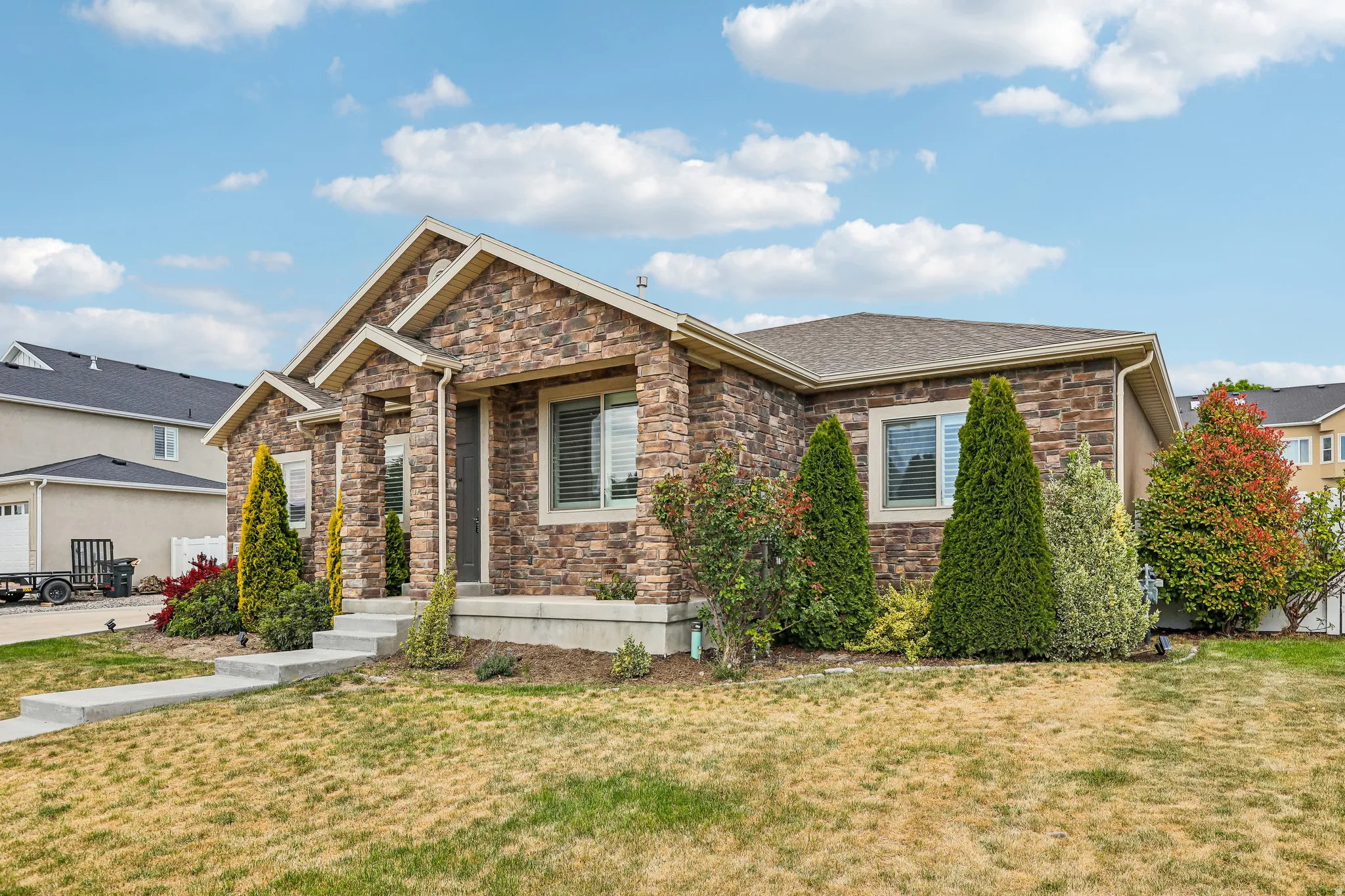 Stone veneer exterior with stucco accents, gabled roofline, and established shrubbery