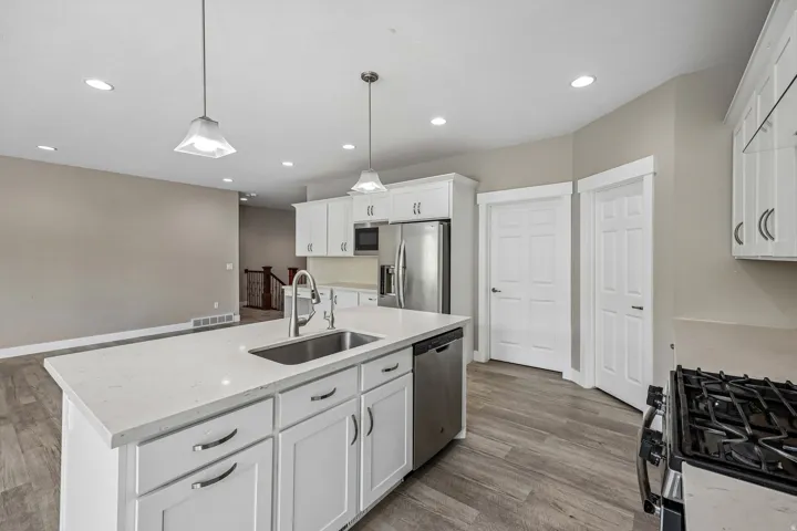 Kitchen with a large island featuring a stainless steel sink and white quartz countertop