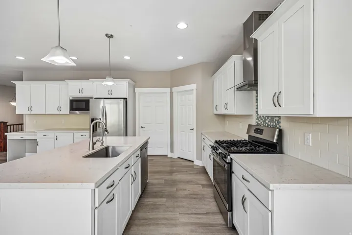 Modern kitchen featuring white cabinetry, light-toned countertops, and wood-finish flooring
