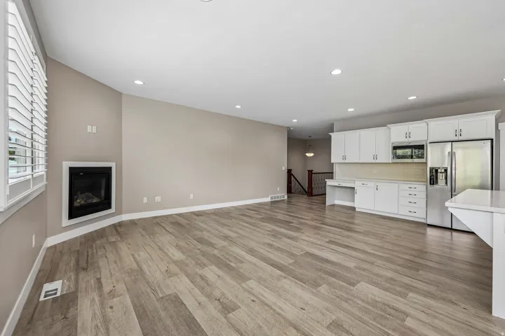 Open-concept living space featuring wood-finish flooring, recessed lighting, and a corner fireplace