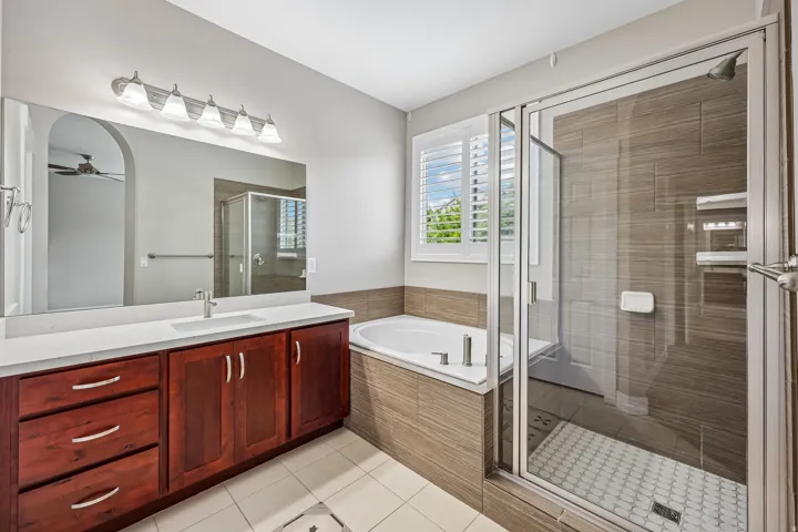 Bathroom featuring a spacious vanity with a white countertop and wood-finish cabinetry, a large mirror, and an overhead light fixture