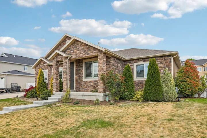 Stone veneer exterior with stucco accents, gabled roofline, and established shrubbery