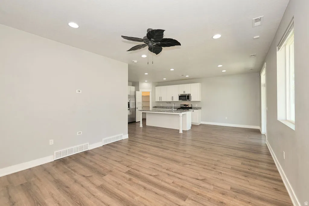 Open-concept living area featuring wood-finish flooring, recessed lighting, and a decorative ceiling fan