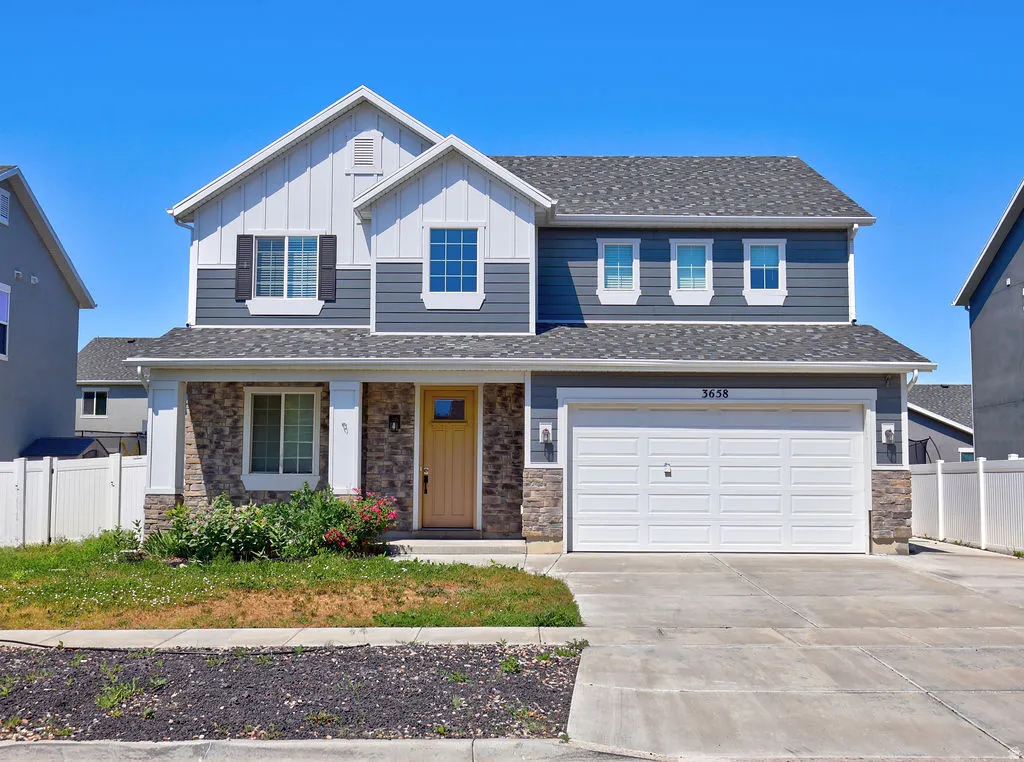 Two-story residence featuring a mixed-material exterior of horizontal siding, vertical board and batten, and stone veneer accents